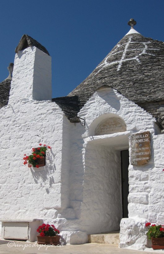 Trullo Siamese.  2 brothers in love with the same woman lived here.  They split it in half and the single brother installed a door into the lane.